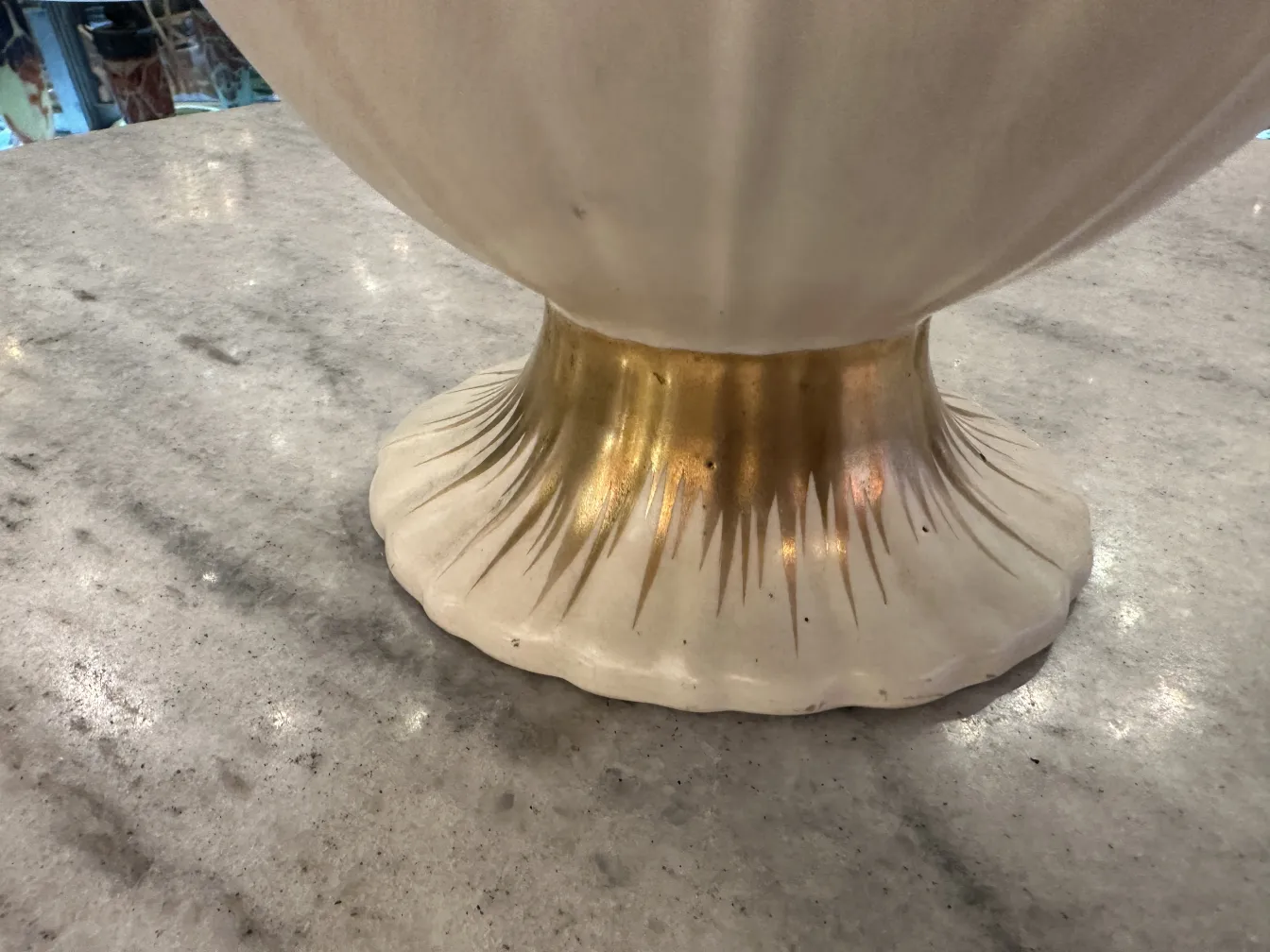 detalle de base de una antigüedad cerámica con un diseño elegante y acabado dorado en un fondo claro