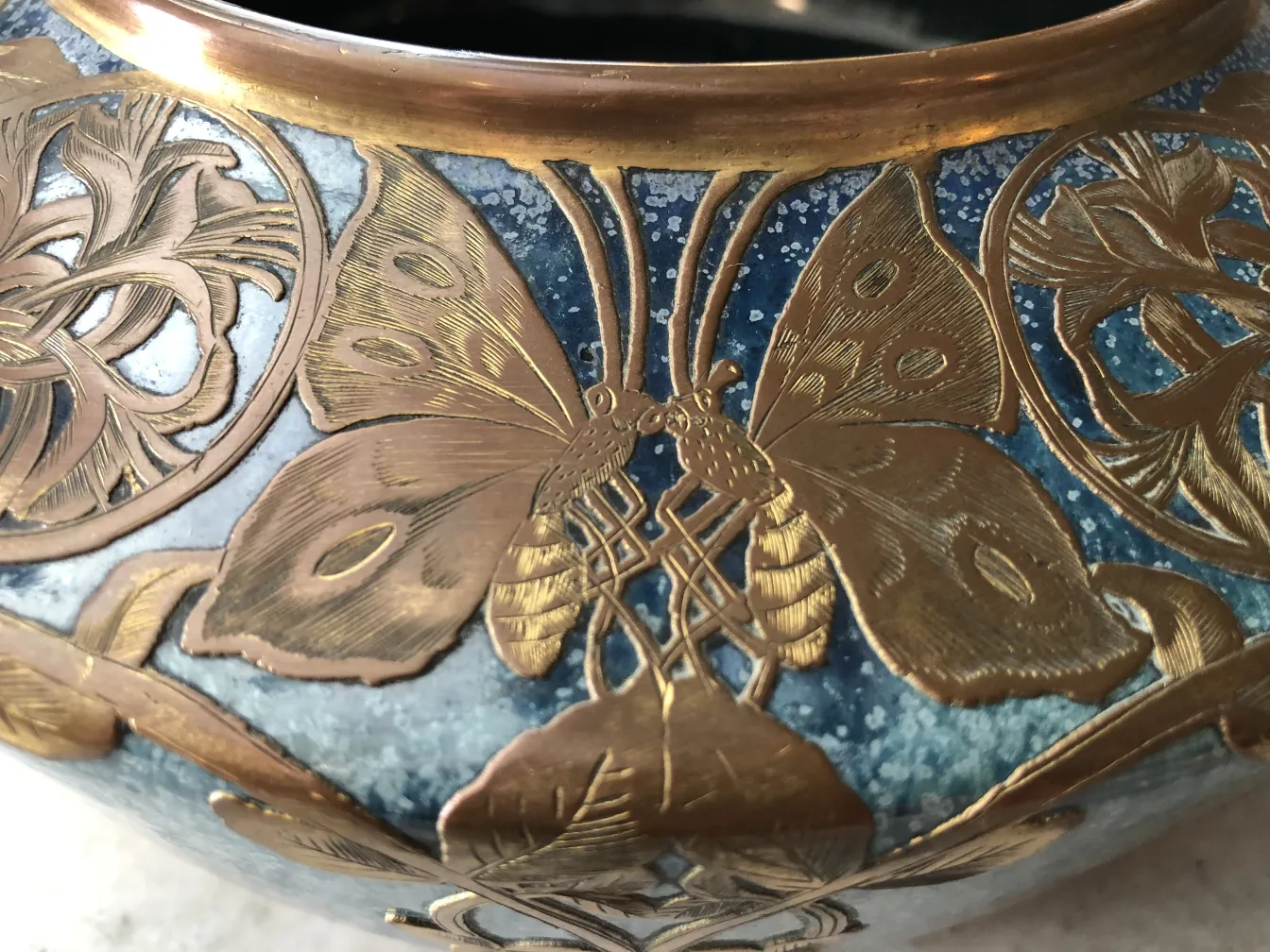 Ancienne céramique ornée d'or et de détails de papillons sur un fond bleu.