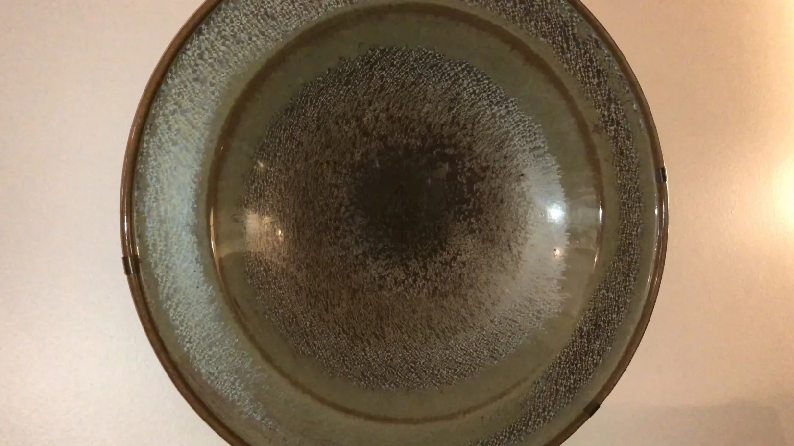 Plato antiguo de cerámica redonda con colores variados en su superficie.