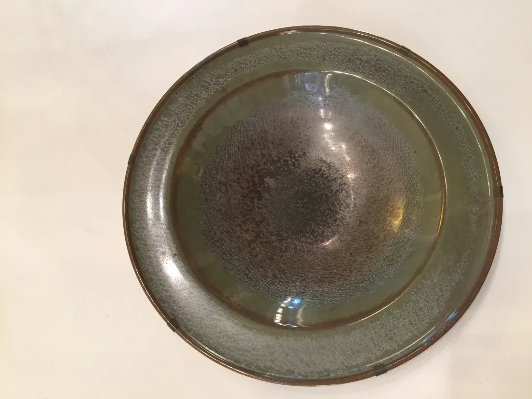 古老的陶瓷椭圆盘，表面有多种棕色和绿色色调