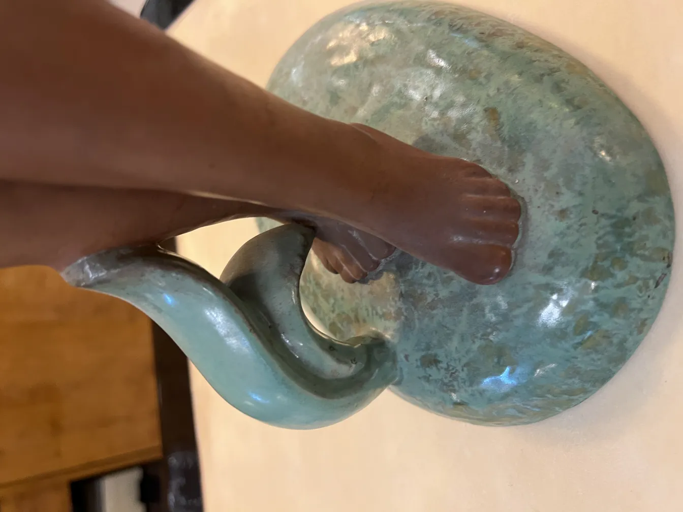 Ceramica antica con design scultoreo e piede decorativo, verde con sfumature.