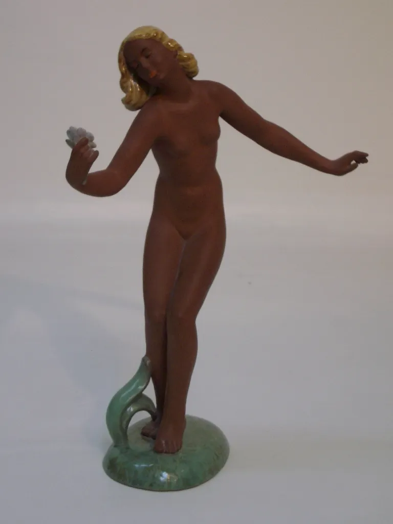 Antica figura femminile in ceramica, in posa elegante con colori caldi.
