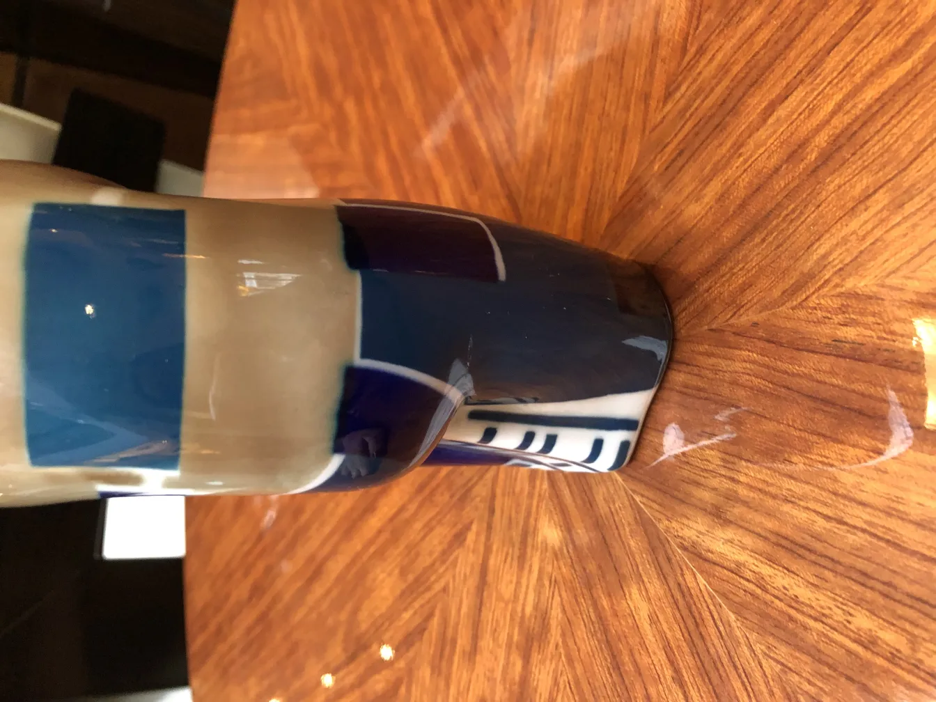 Ancienne céramique décorative avec des motifs bleus sur fond clair, placée sur une table en bois.