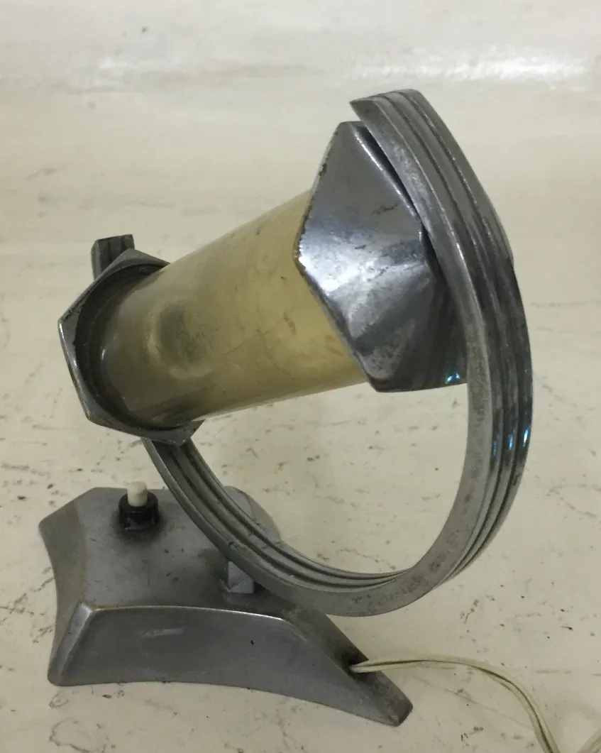 lampe de bureau ancienne avec un design circulaire et une base stable, entourée d'un environnement neutre