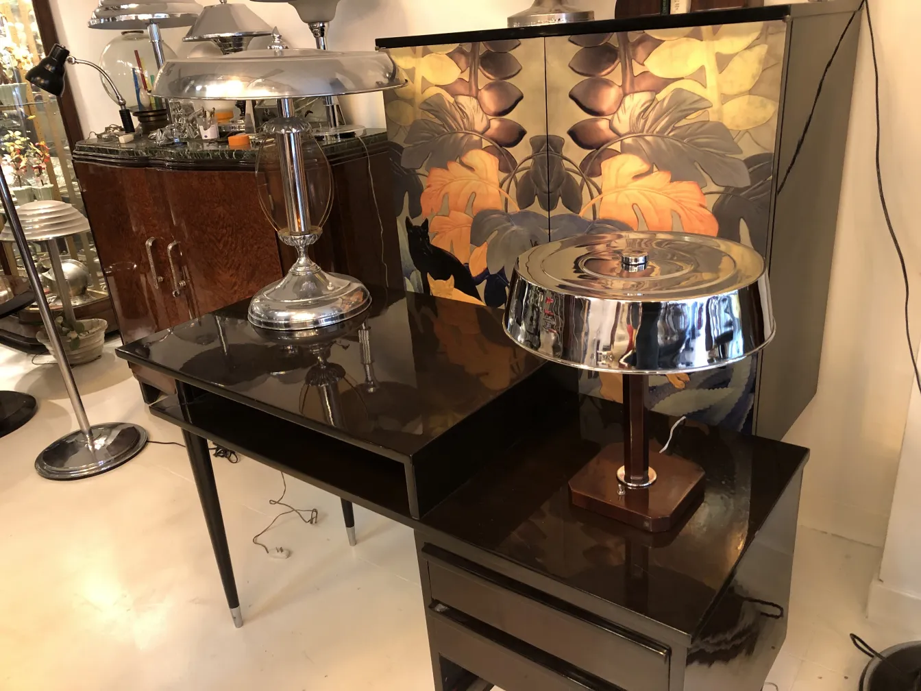 Antigua lámpara de mesa brillante sobre escritorio negro con fondo decorativo.