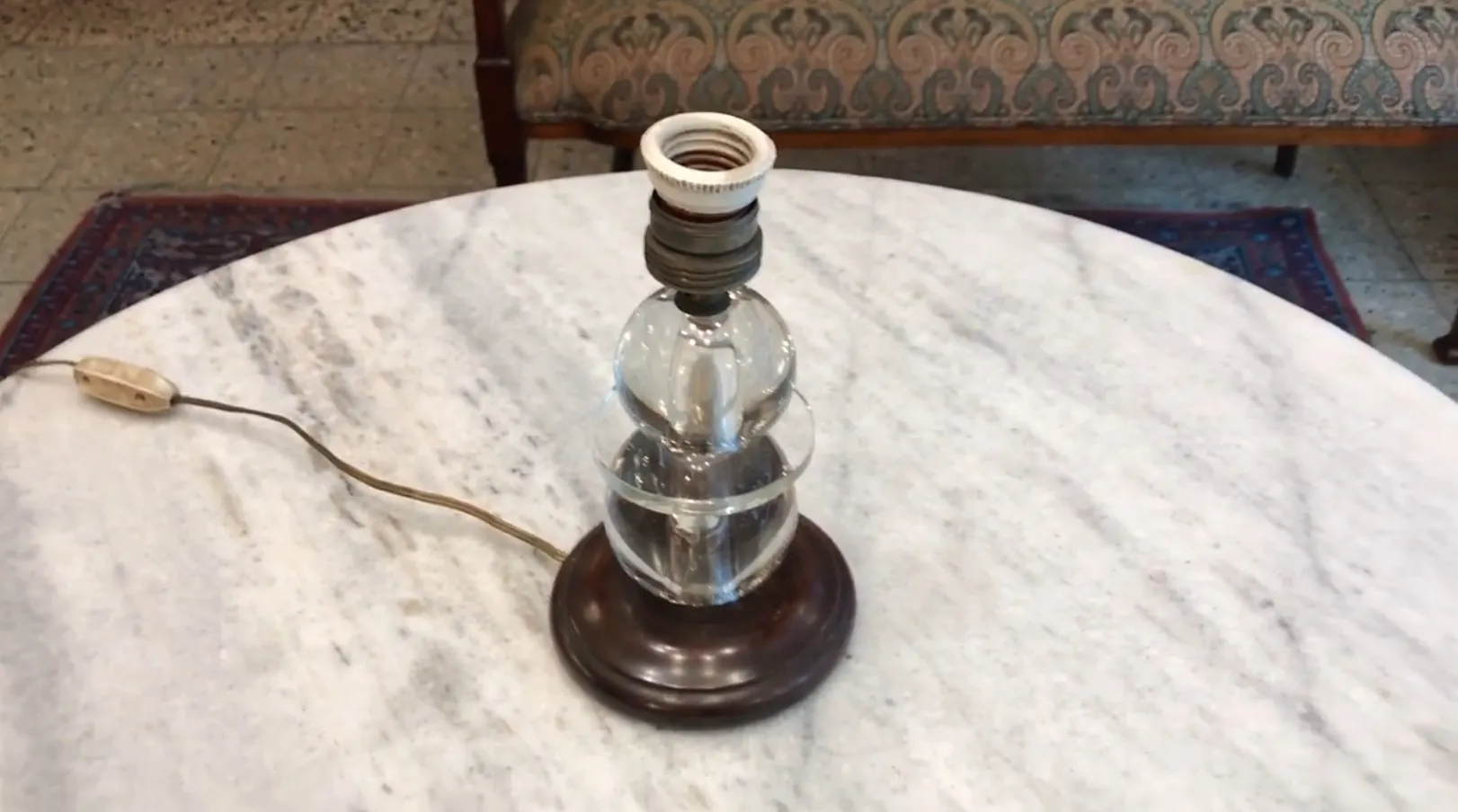 antique table lamp with round base and visible bulb on marble surface