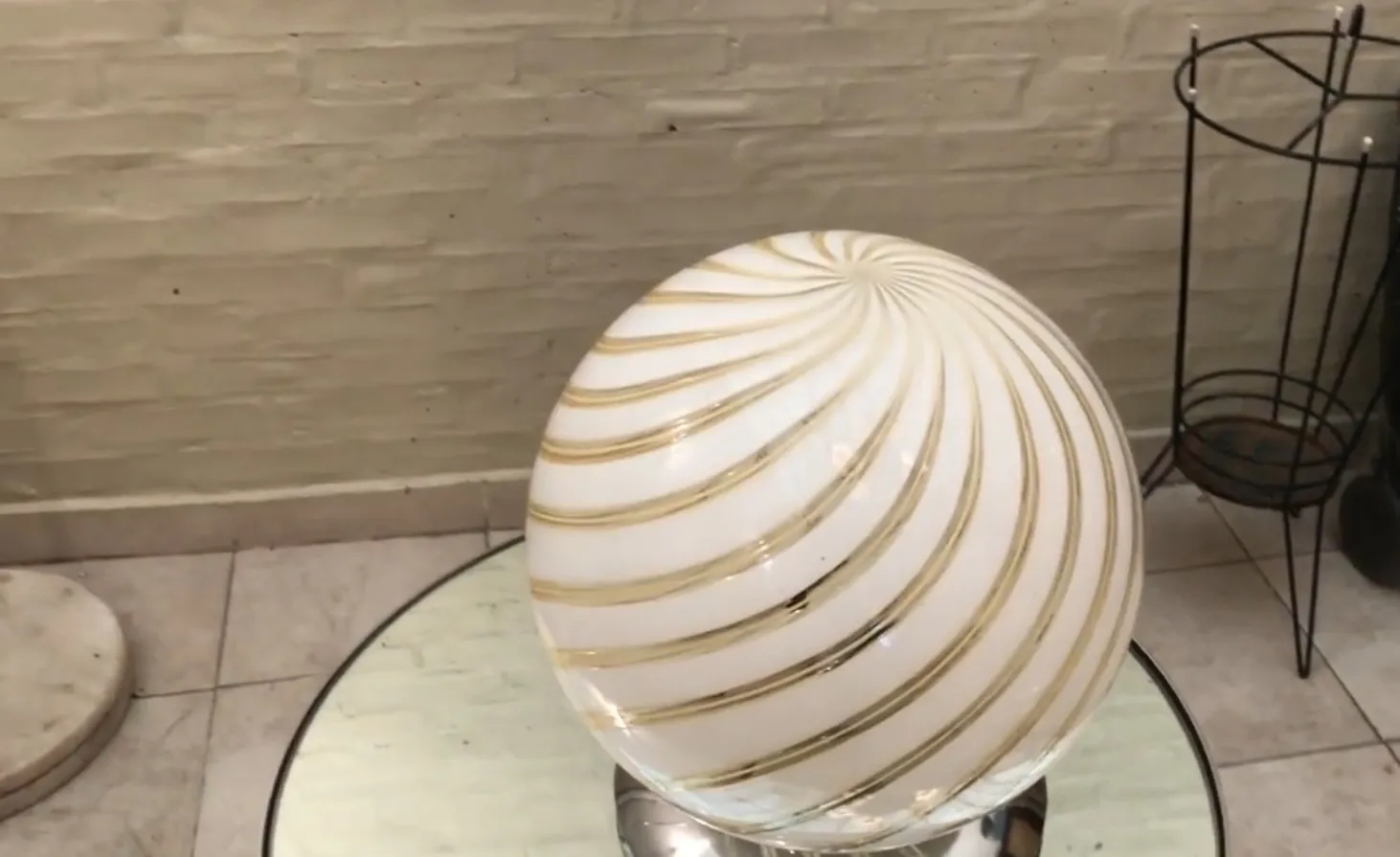 Lampe de bureau ancienne avec design en spirale et accents dorés, accompagnée d'objets décoratifs en arrière-plan.