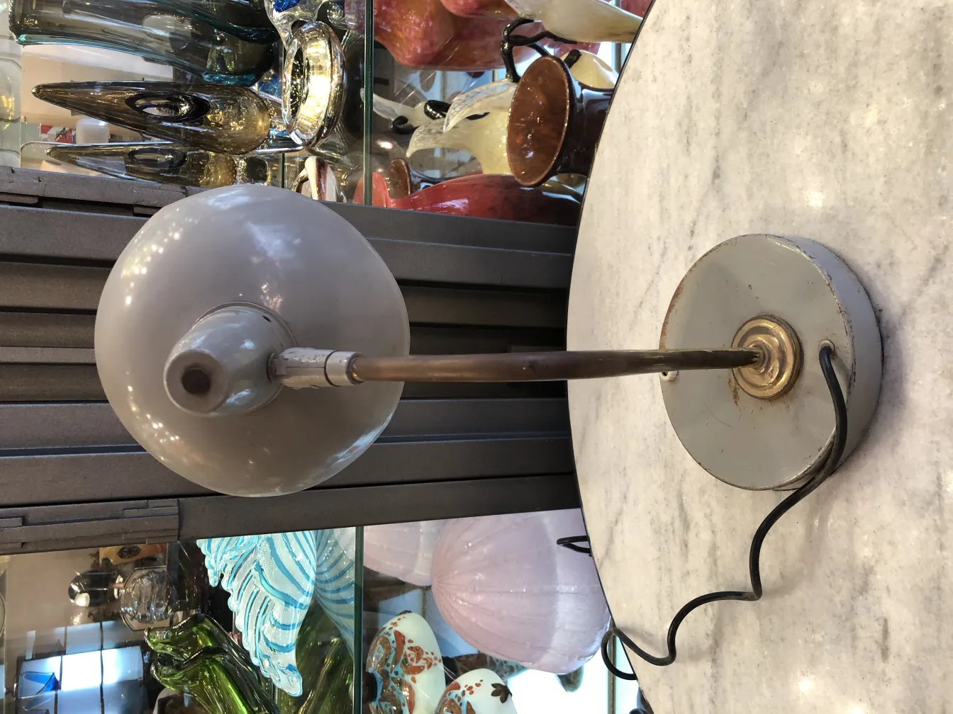 Antique table lamp with round base and elegant design, surrounded by decorative items.