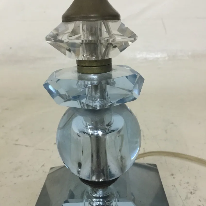 Lámpara de mesa antigua con detalles decorativos en cristal, entorno neutro.