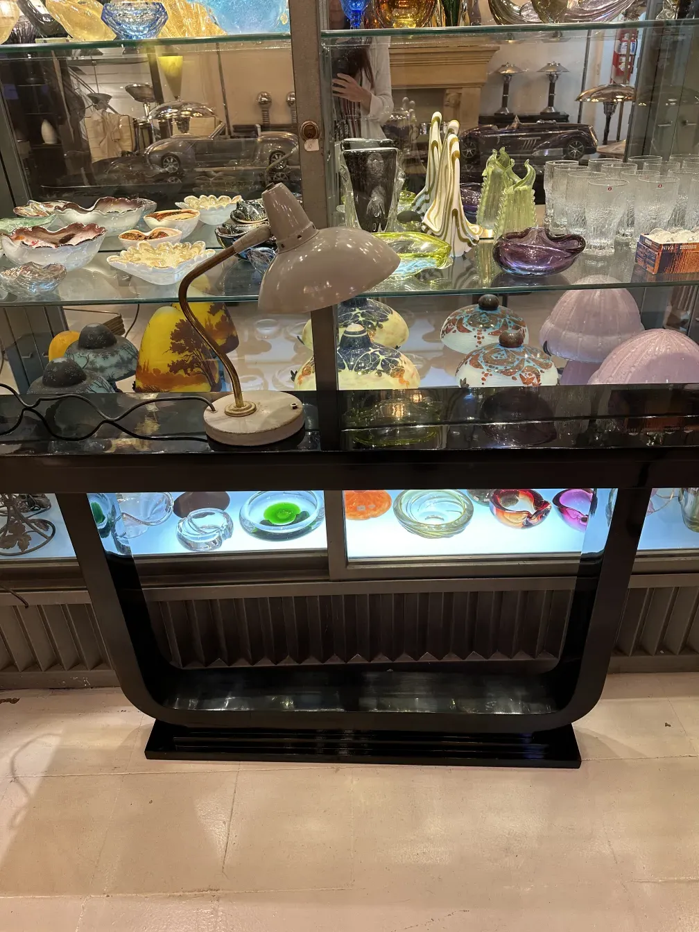 Lámpara de mesa antigua de Serge Mouille con diseño curvo, situada sobre una mesa con objetos decorativos.