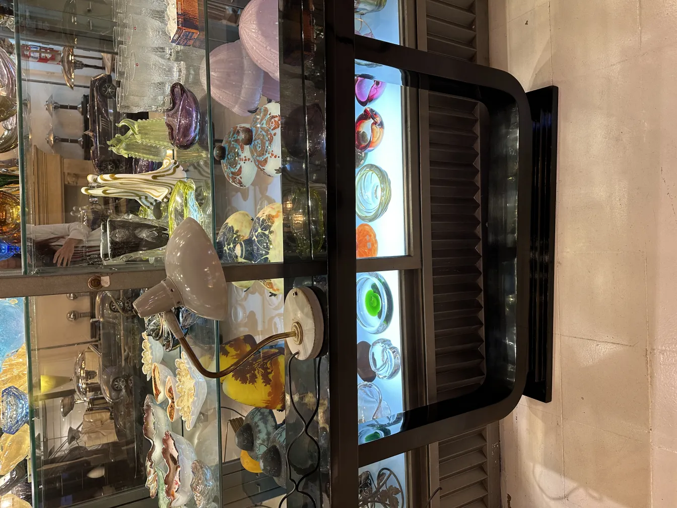 प्राचीन टेबल लैंप, जहाँ नरम रोशनी और कलात्मक आधार होता है, इस प्रकार सजावटी वस्तुओं से घिरा होता है