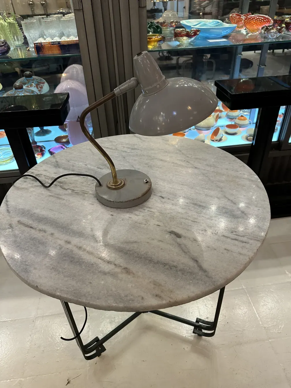 Lampada da tavolo antica di Serge Mouille con base curva su tavolo rotondo, ambiente accogliente.