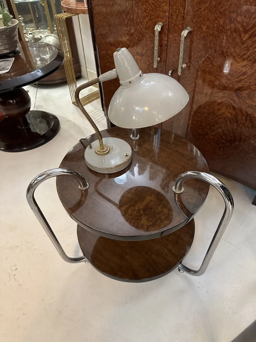 Lampe de bureau ancienne avec base circulaire et abat-jour blanc dans un cadre élégant.