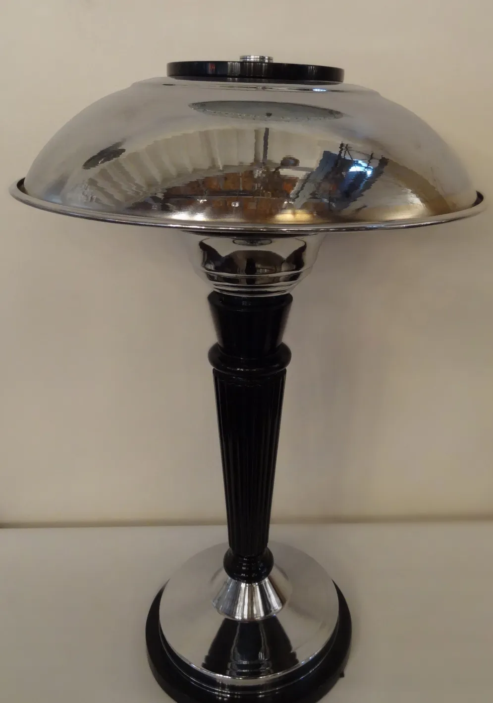 Lámpara de mesa antigua con diseño elegante y base brillante en un ambiente sencillo.