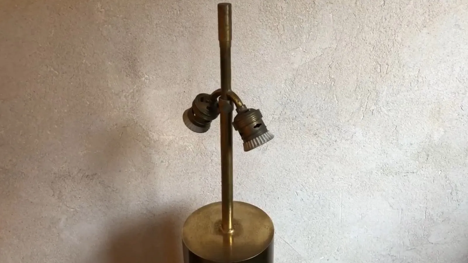 Antique table lamp with a design featuring two arms, in a simple decorative setting.