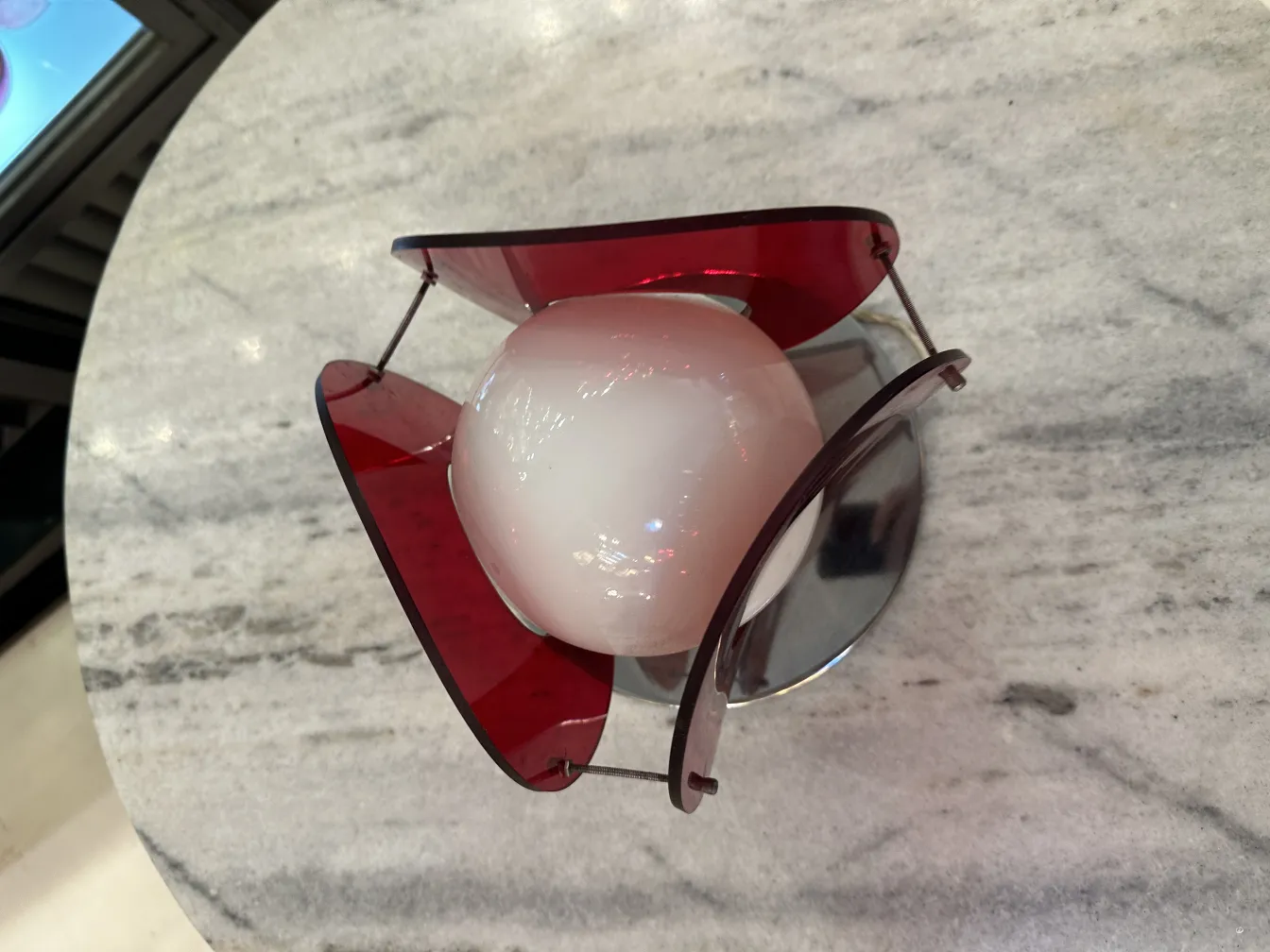 Lámpara de mesa antigua con diseño colorido sobre fondo de mármol.