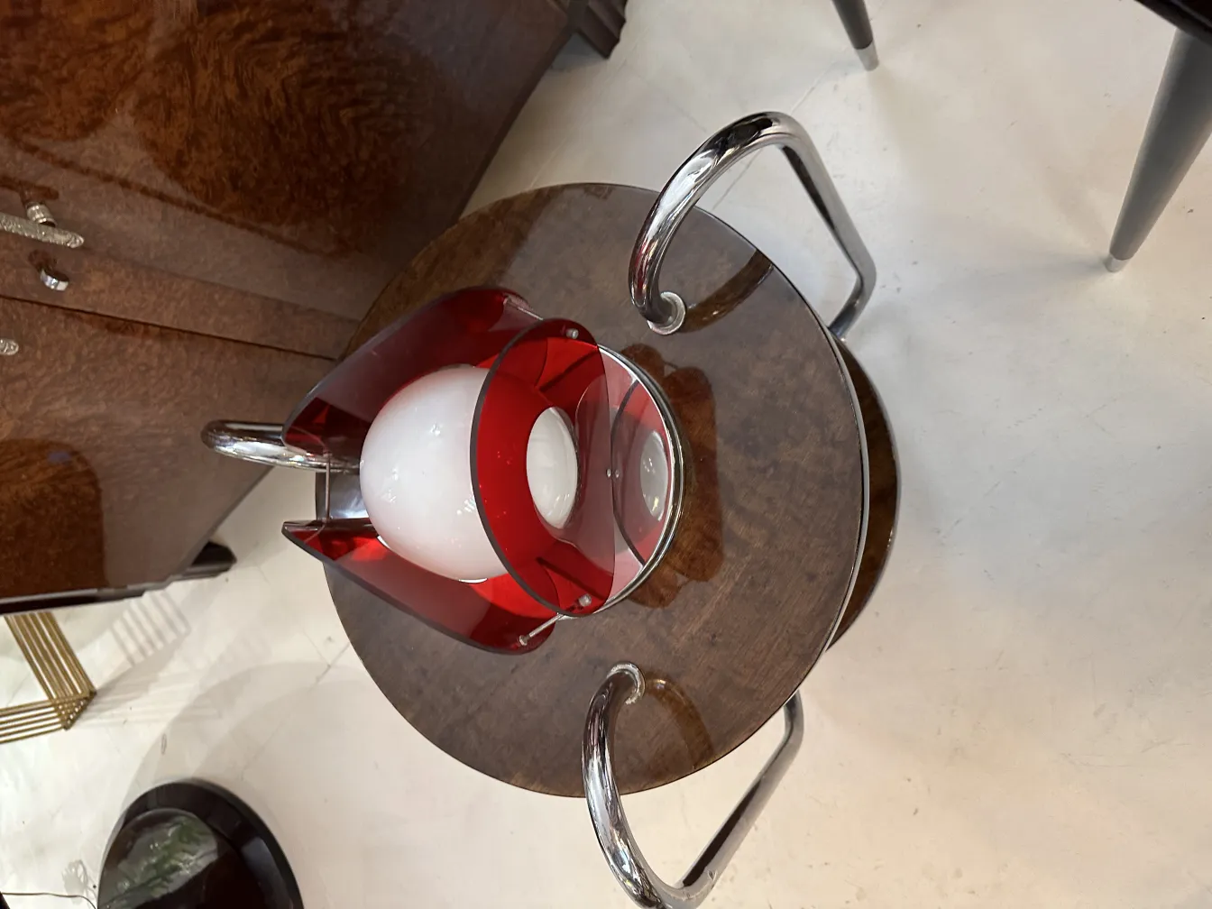 antique table lamp with a round base and red details, next to a wooden table