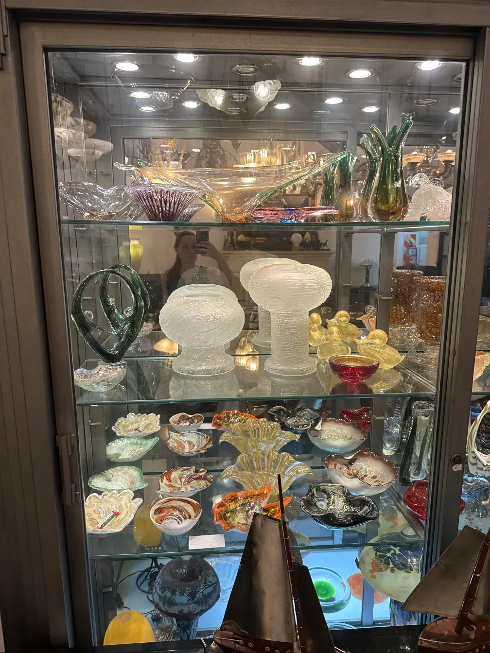 古老的桌灯，带有玻璃设计，周围环绕着其他装饰物品。