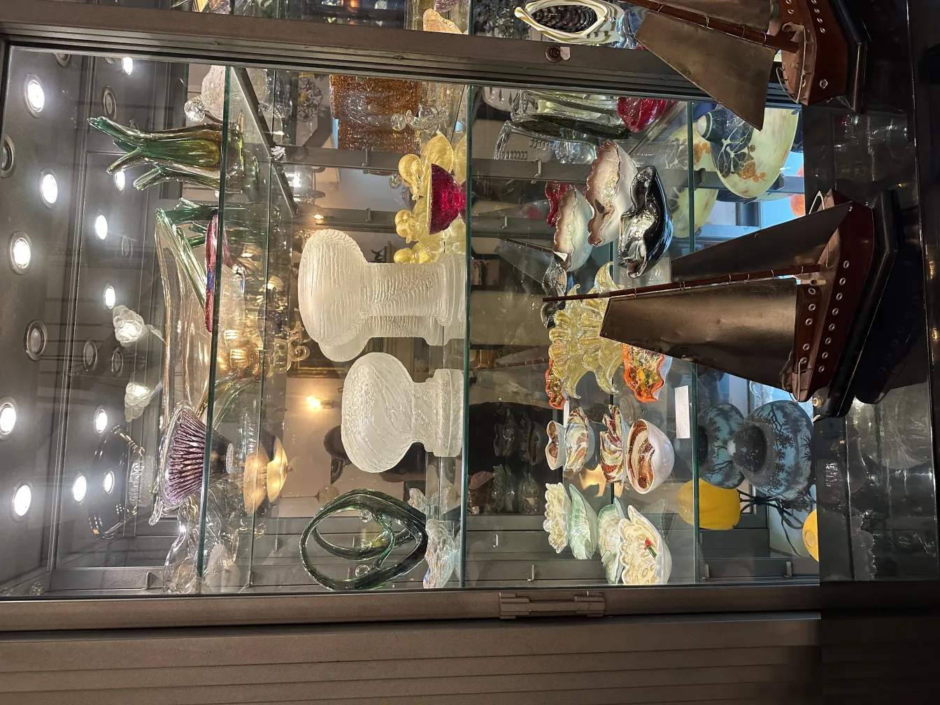 Luminária de mesa antiga com detalhes decorativos, em um ambiente elegante com objetos de vidro.