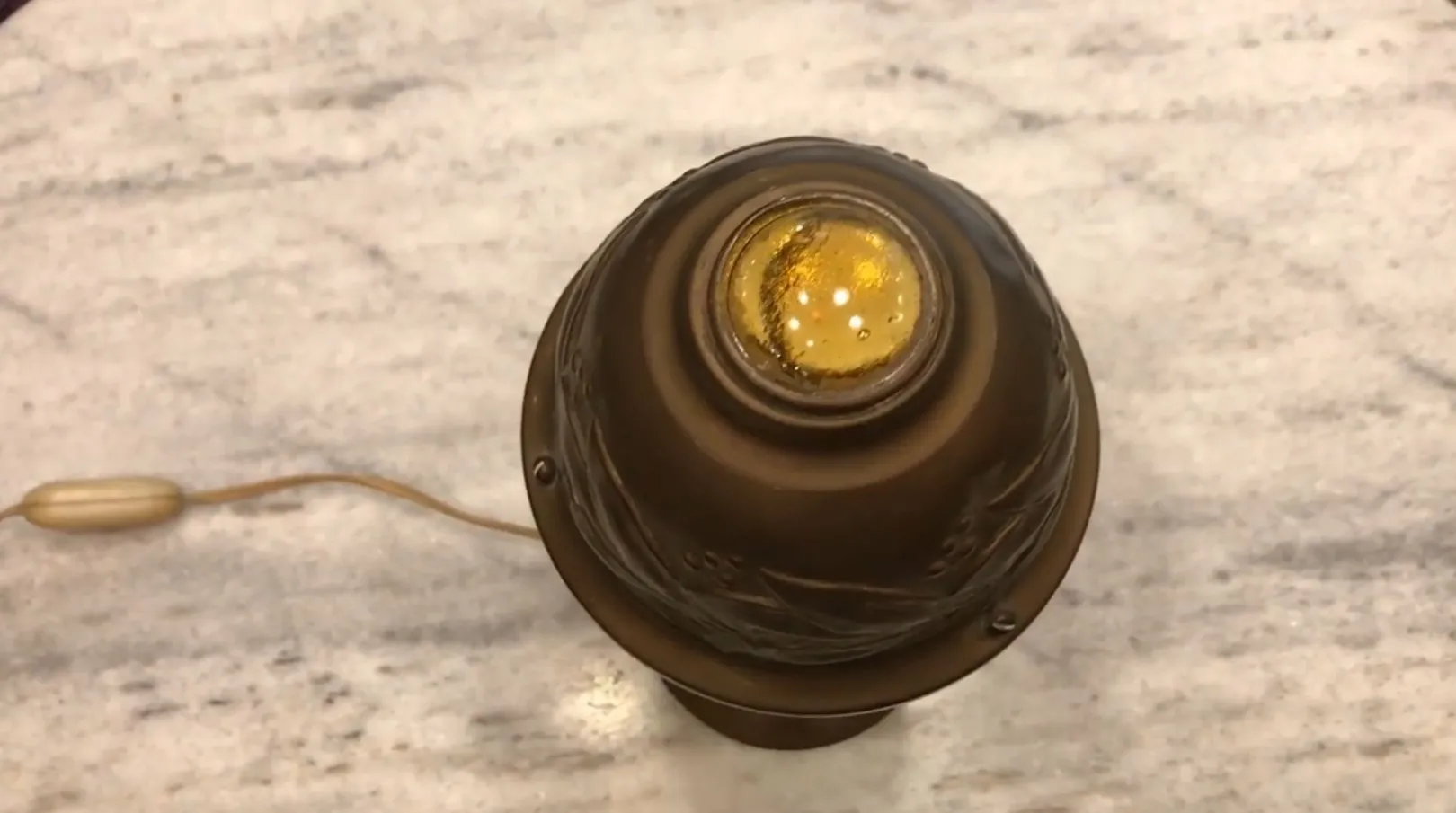 Lámpara de mesa antigua con luz amarilla en la parte superior.