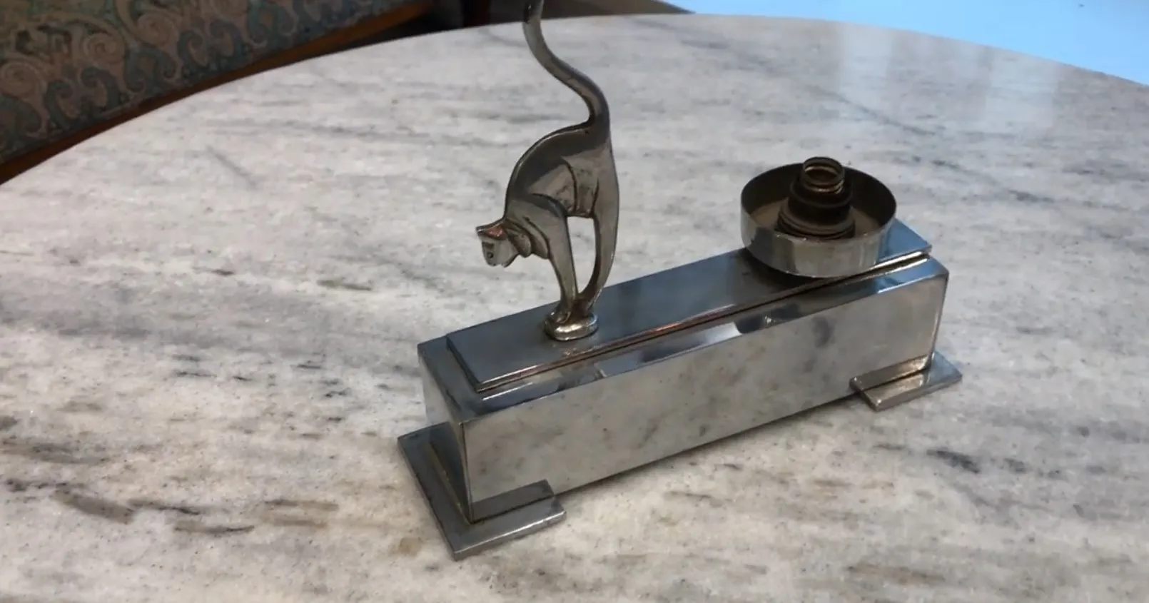 Lámpara de mesa antigua con un diseño de gato, sobre una mesa de mármol.