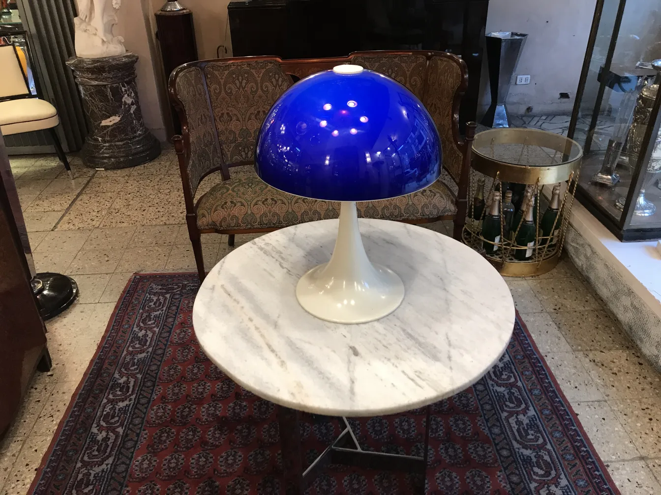 Lampada da tavolo antica con paralume blu su un tavolo in marmo.