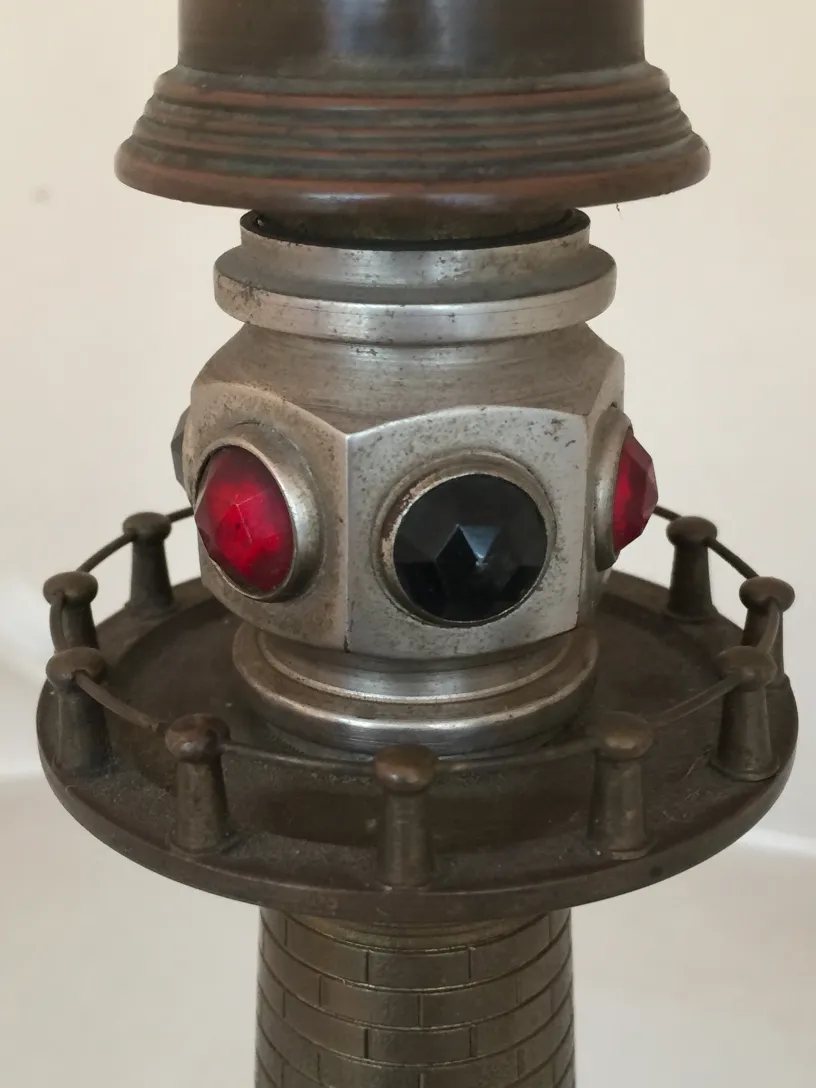 Dettaglio di una lampada da tavolo antica con accenti di gioielli rossi e neri alla base, decorazioni classiche