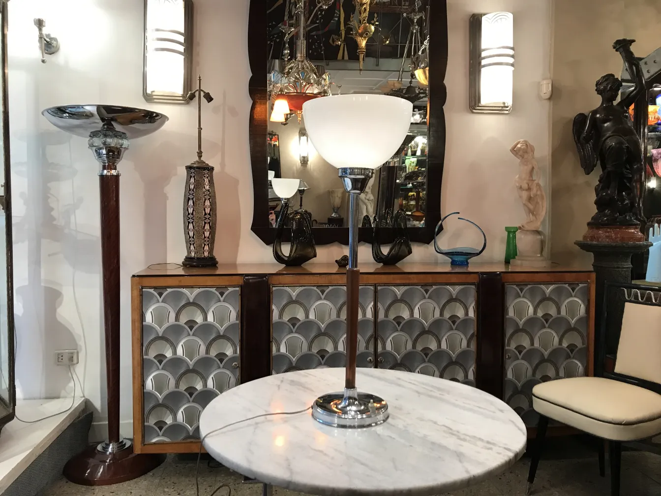 Elegante lámpara de mesa antigua junto a un espejo con diversos objetos decorativos.