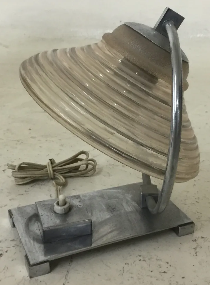 Antike Tischlampe mit gewölbtem Schirm und Metallbasis in einem einfachen Umfeld