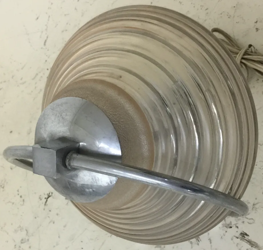 مصباح طاولة قديم بتصميم إهليلجي وبنية معدنية، يضيء البيئة.