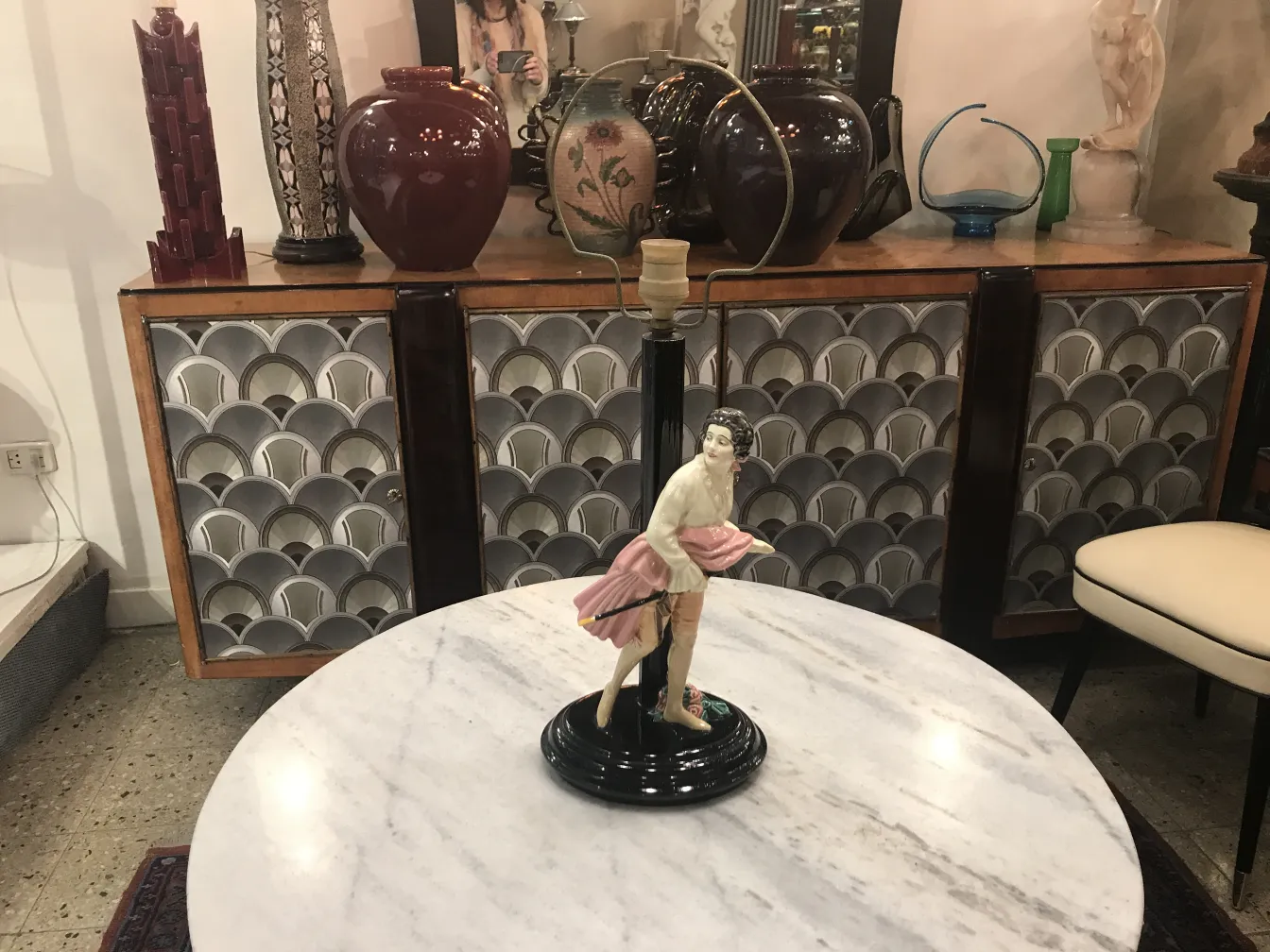 Lámpara de mesa antigua con figura decorativa sobre base negra.