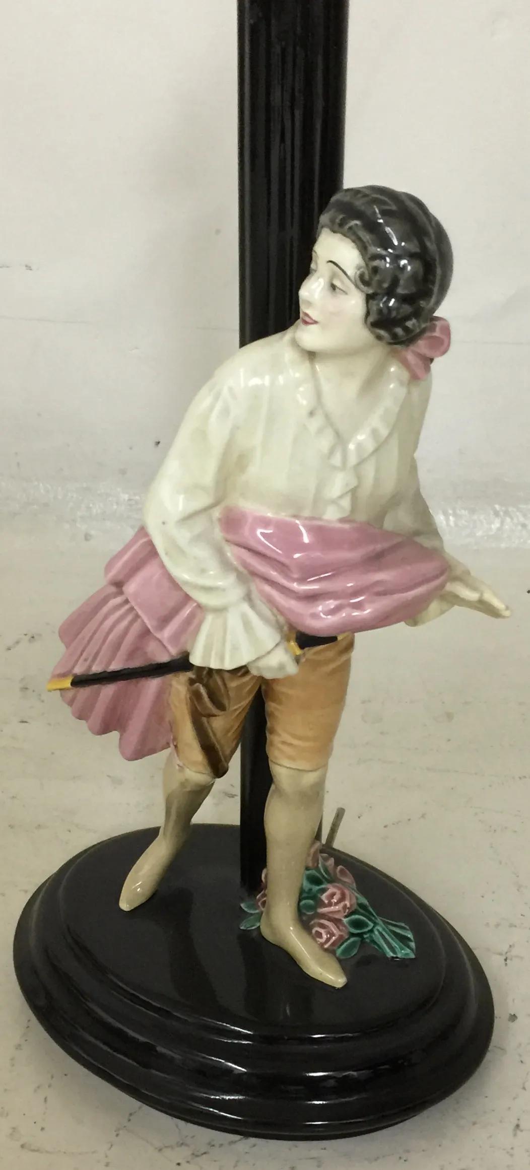 Lámpara de mesa antigua con figura femenina en color claro y base negra.