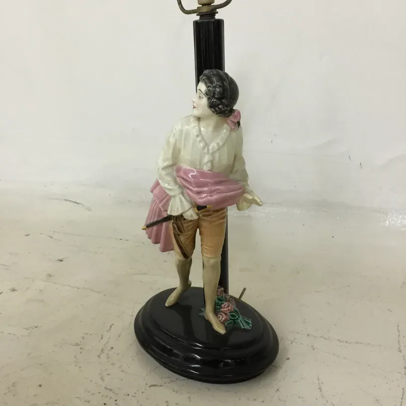 Lampada da tavolo antica con figura decorativa che tiene un ombrello rosa.