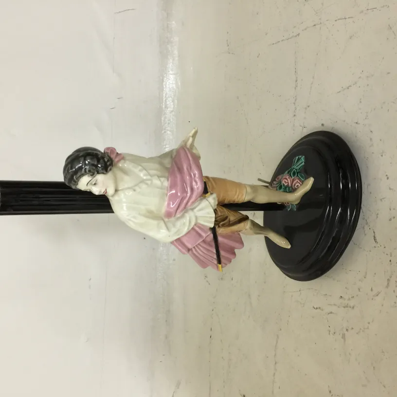 Antike Tischlampe mit dekorativer Figur und bunten Details.