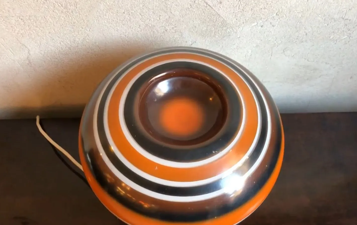 Lámpara de mesa antigua con diseño redondeado y colores vibrantes sobre una superficie de madera