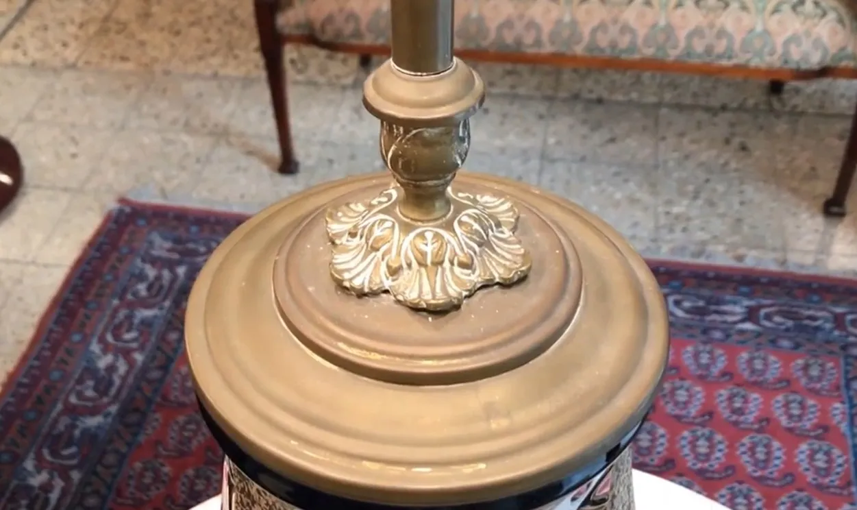 Lámpara de mesa antigua con base decorativa y ornamentos en el diseño, en un ambiente clásico