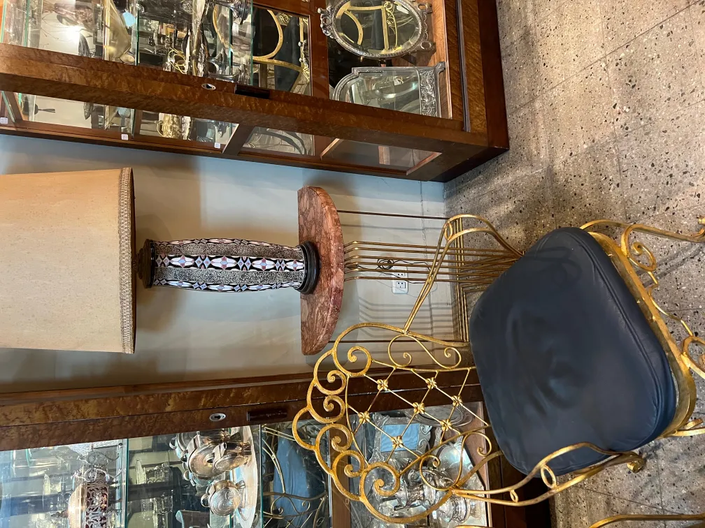 lampe de bureau ancienne avec abat-jour beige et base décorée, dans un environnement d'antiquités