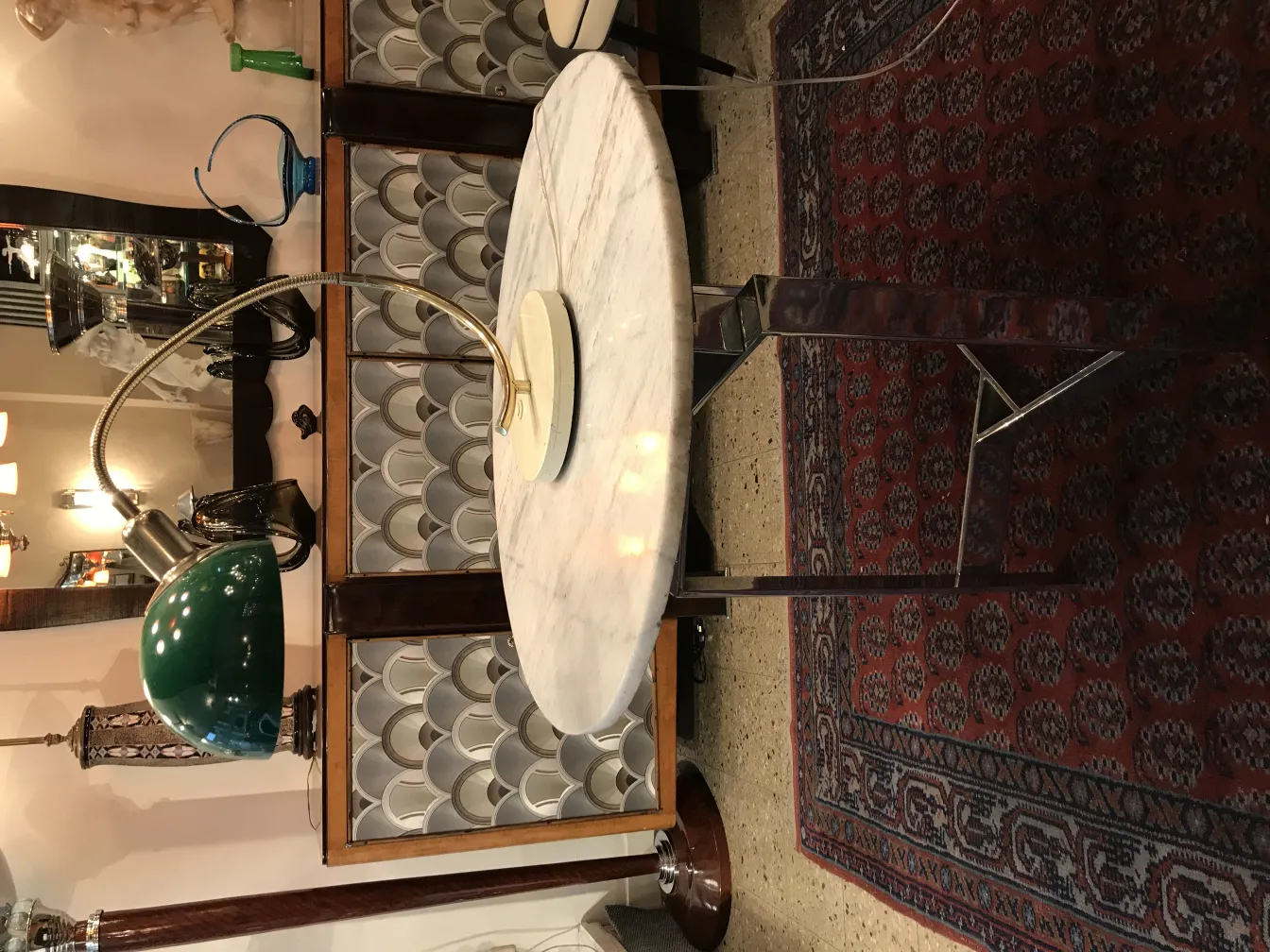 Lámpara de mesa antigua con base redonda y brazo flexible, en un ambiente vintage con alfombra oriental.