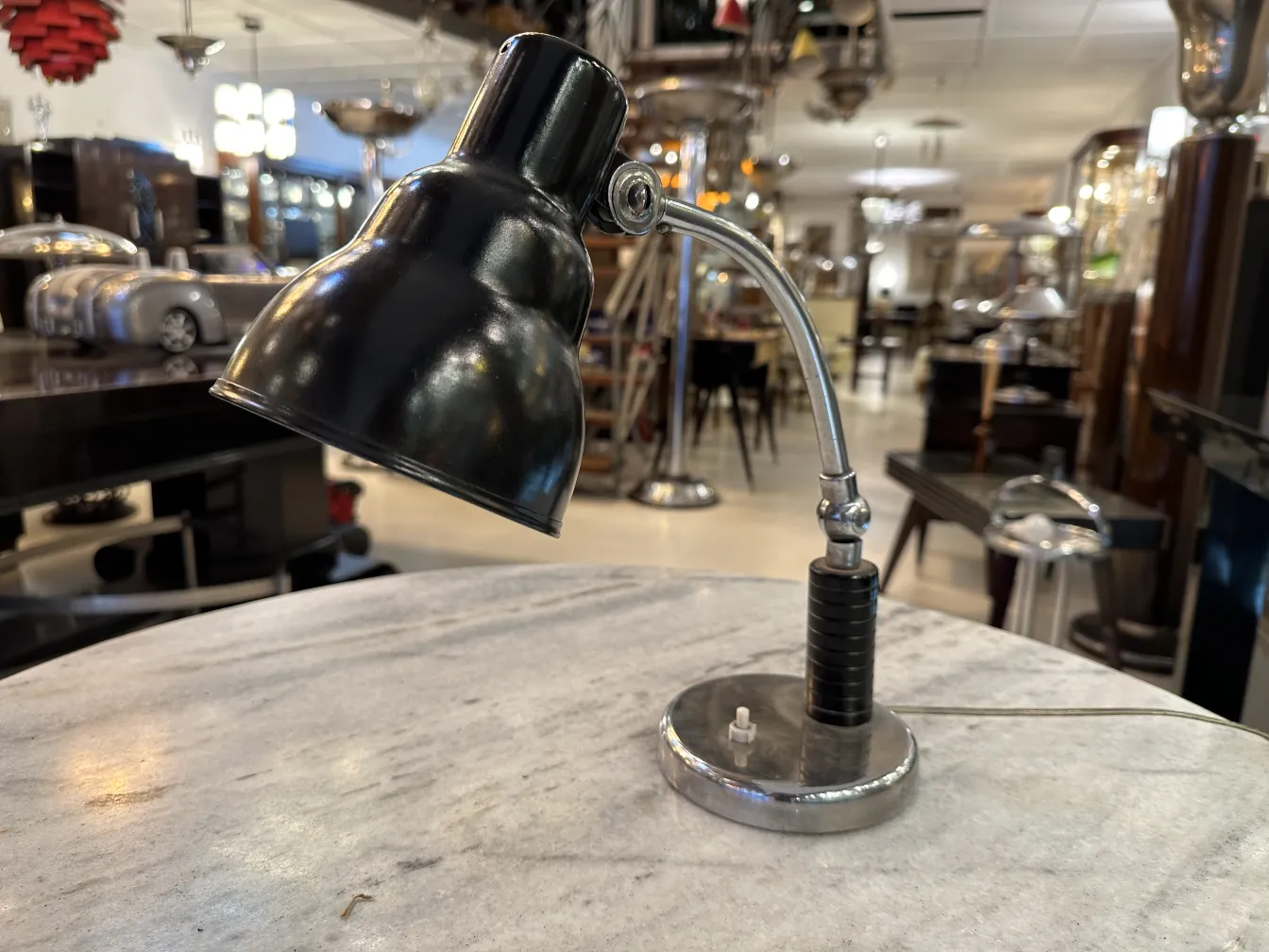 Lámpara de mesa antigua con base metálica y sombra negra, en un ambiente decorativo.