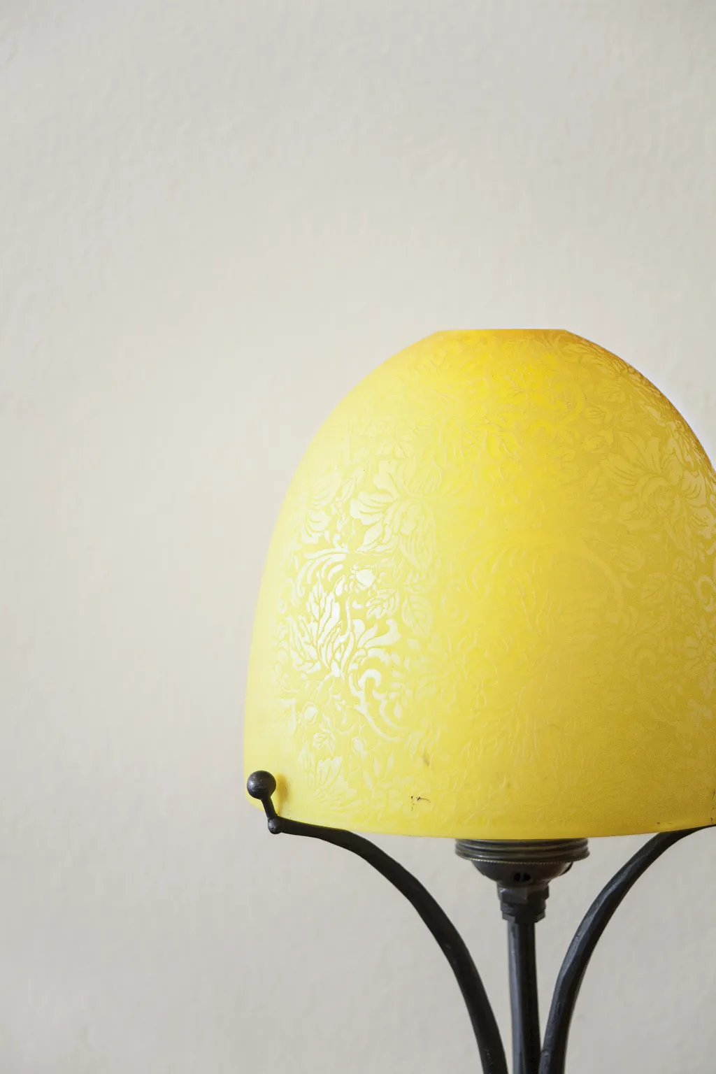 Antica lampada da tavolo con paralume giallo decorativo, sfondo neutro.
