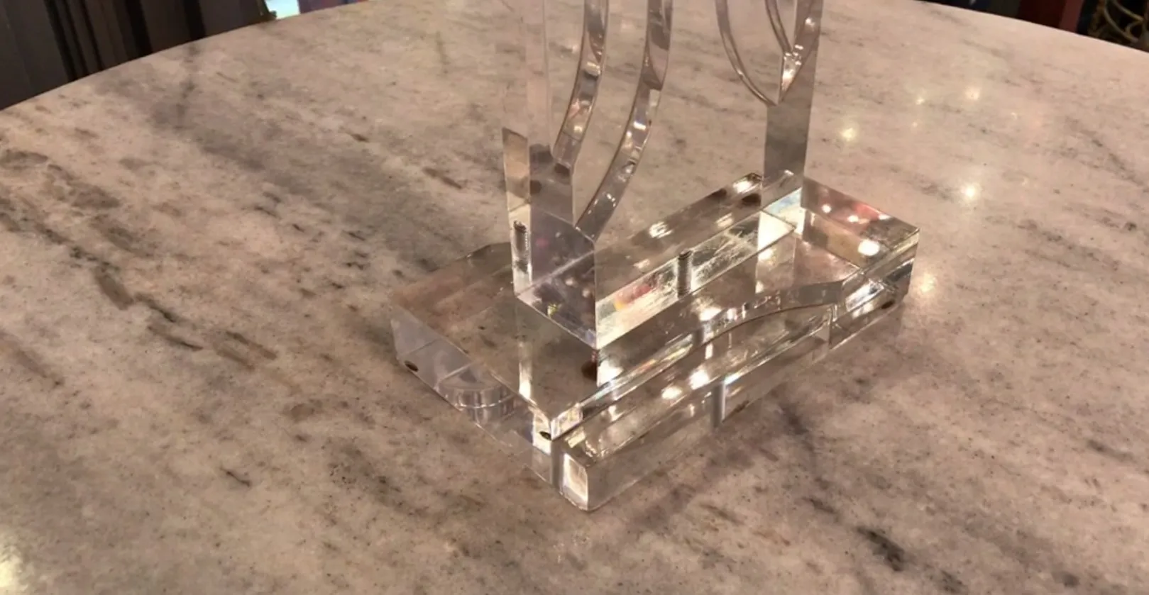 Lampada da tavolo antica con base trasparente su una superficie chiara, ambiente elegante.