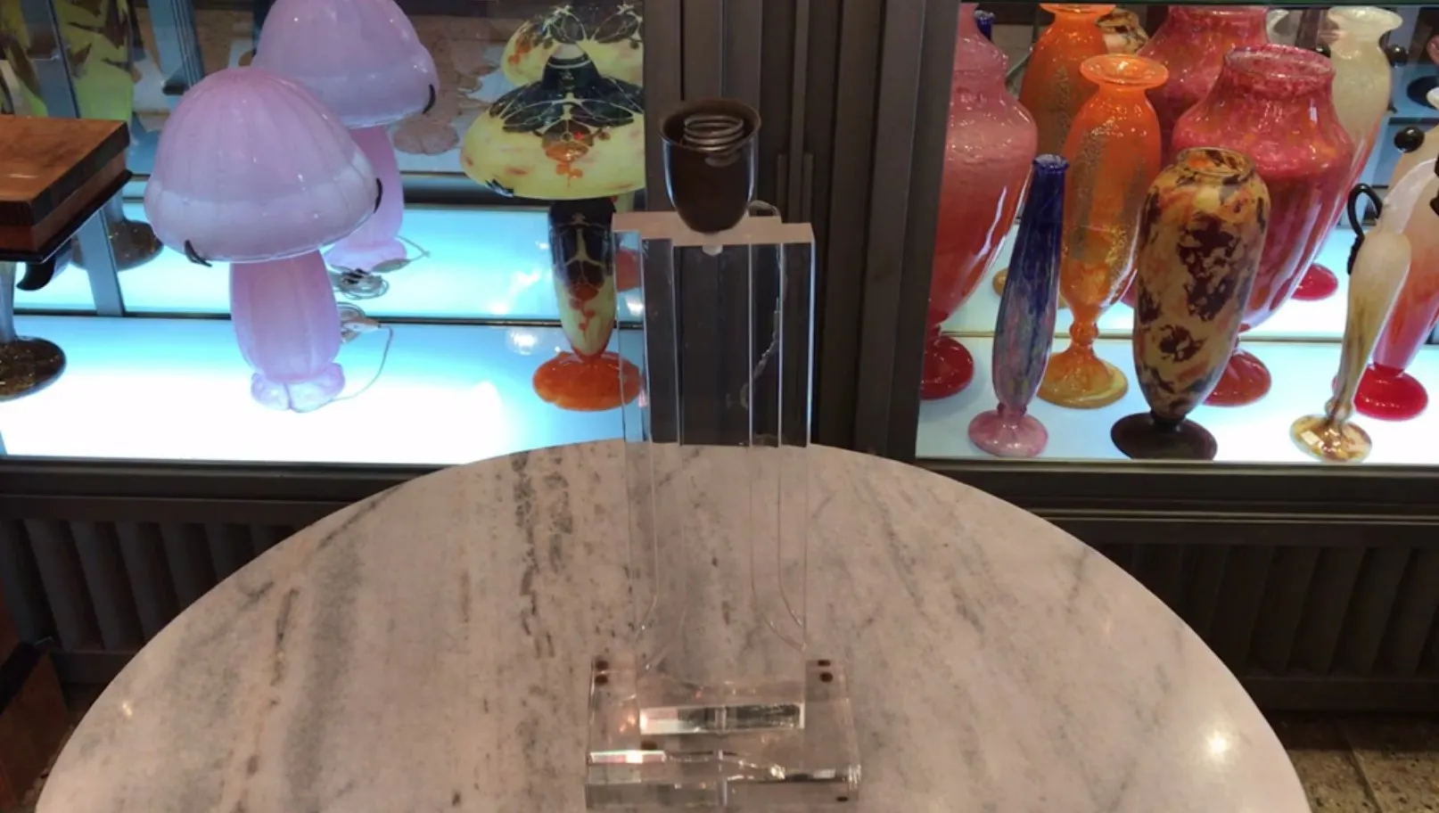 古董粉色台灯配有玻璃底座，照亮背景中的彩色装饰盘