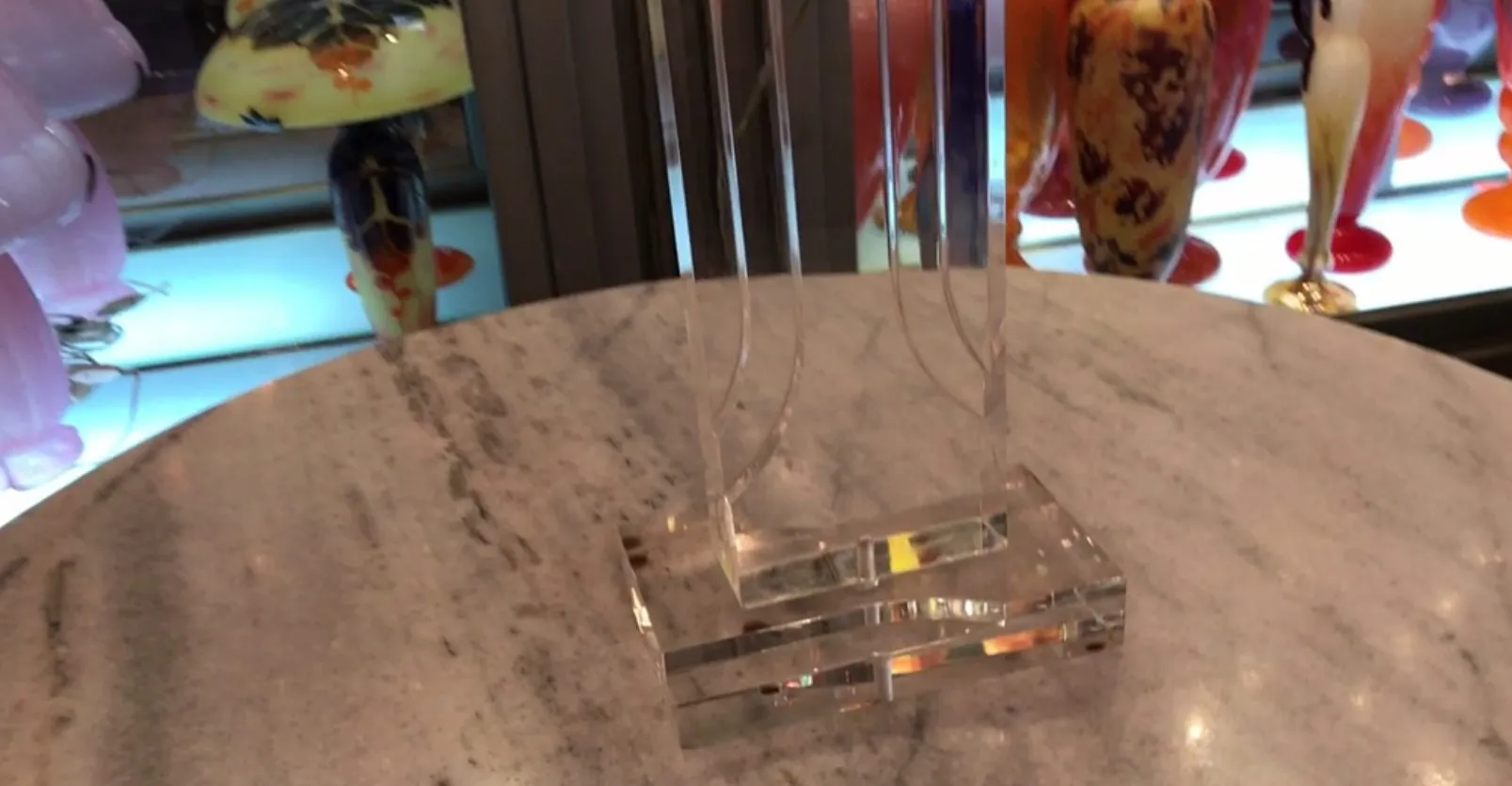 Lámpara de mesa antigua con base transparente sobre mesa.