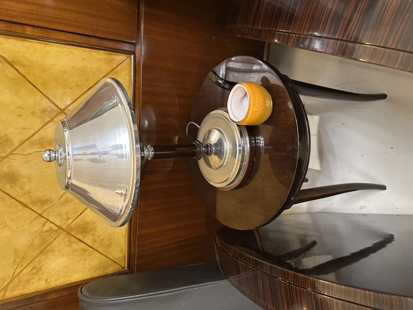 Luminária de mesa antiga com cúpula de metal brilhante e base decorativa sobre mesa