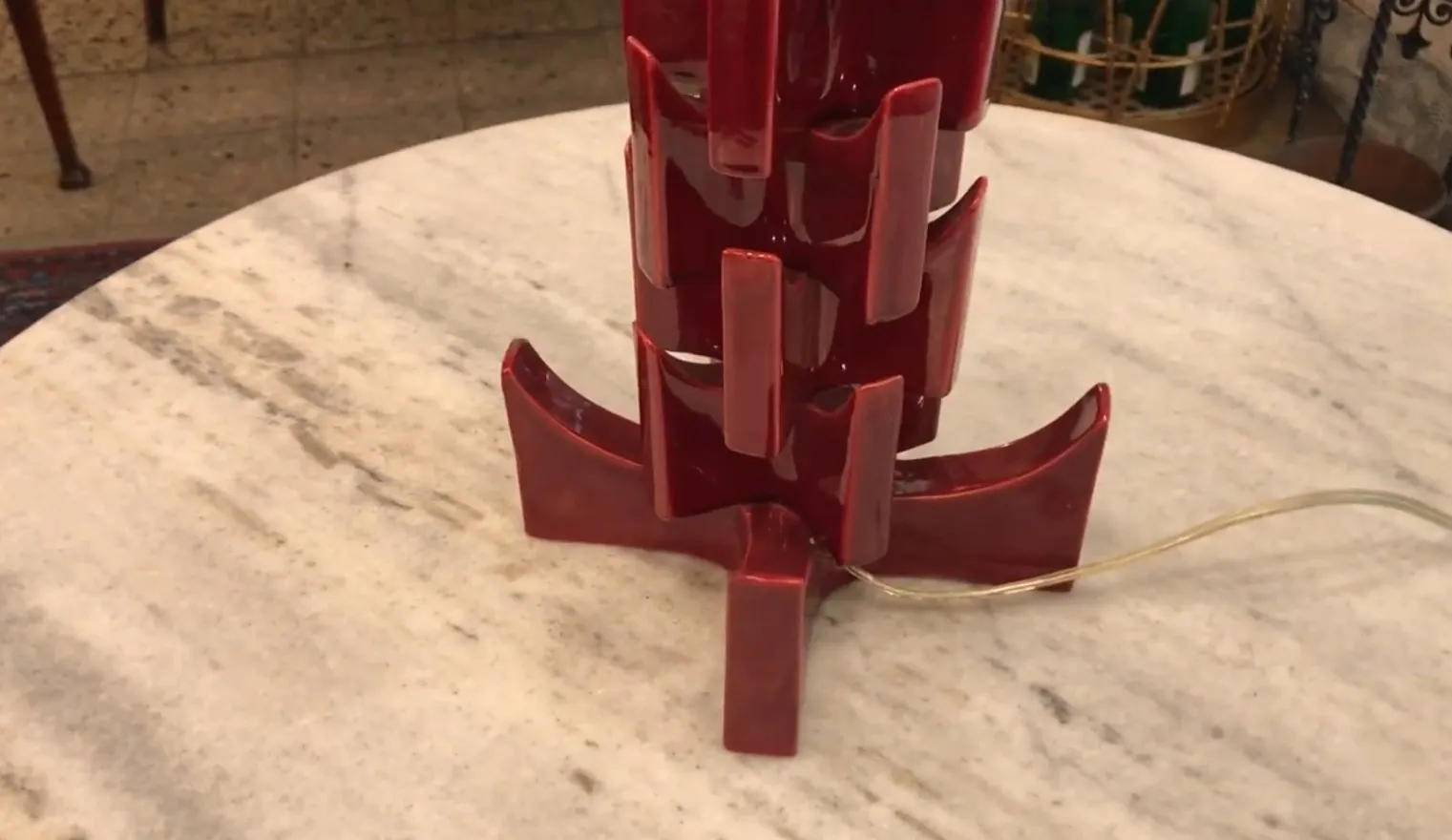 Lampada da tavolo antica rossa con un design unico su un tavolo in marmo.