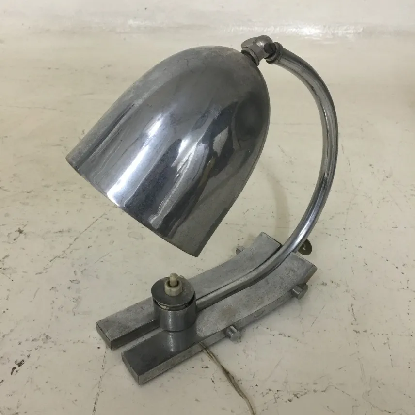 lampada da tavolo antica lucida con base elegante e paralume curvo, posizionata su una superficie chiara