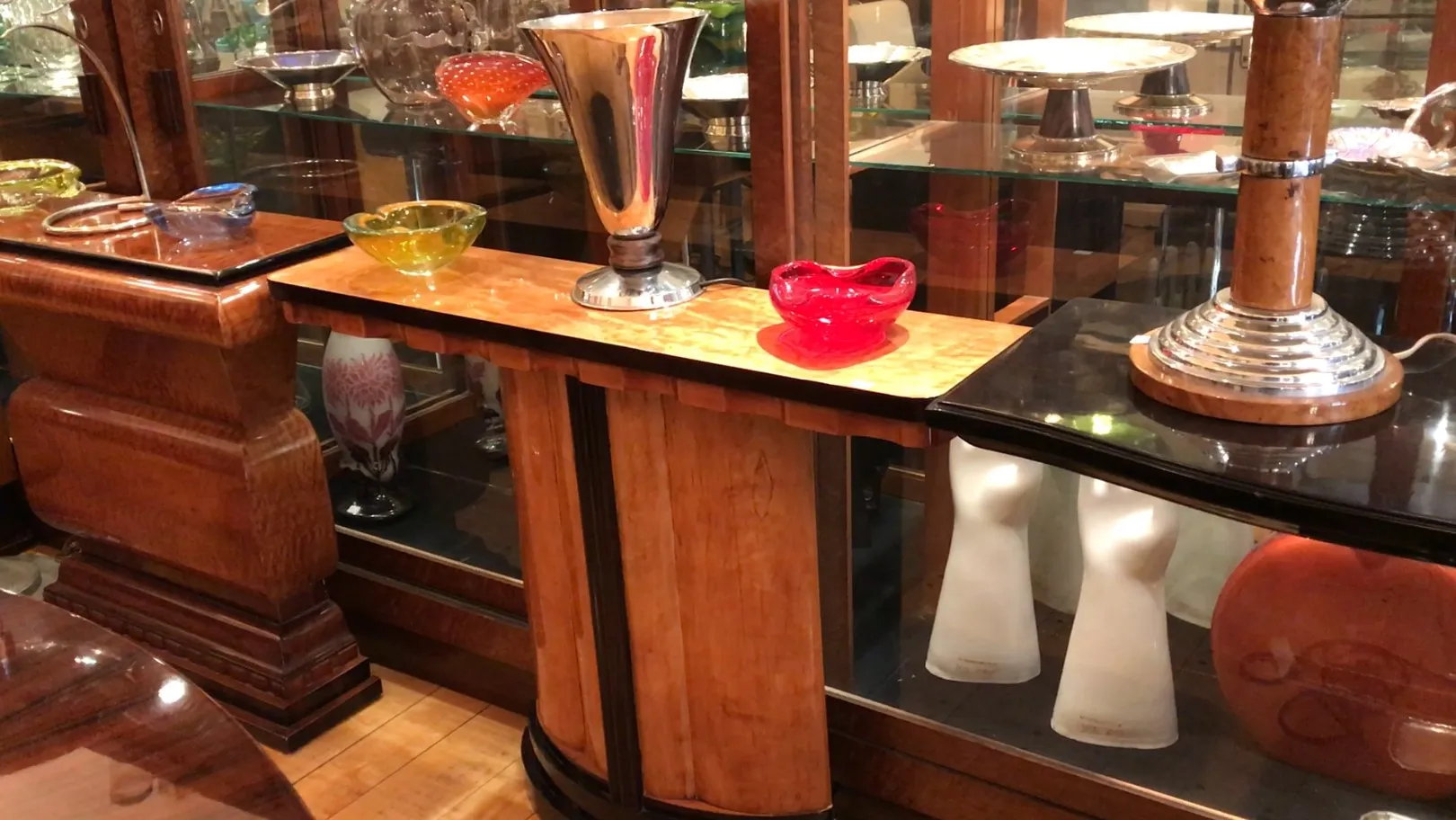 An antique table lamp with an elegant base, surrounded by decorative objects.