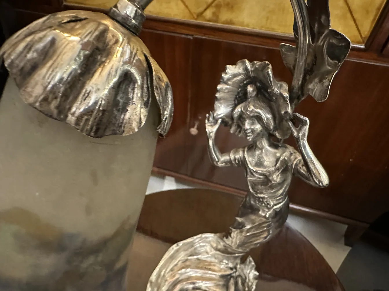 Lampe de bureau ancienne avec une figure féminine et des détails brillants dans un cadre classique.