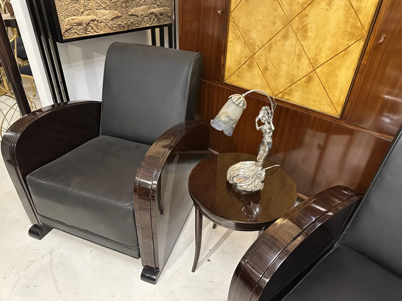 Lampada da tavolo antica con figura femminile muller fres accanto a un tavolo e poltrone di design