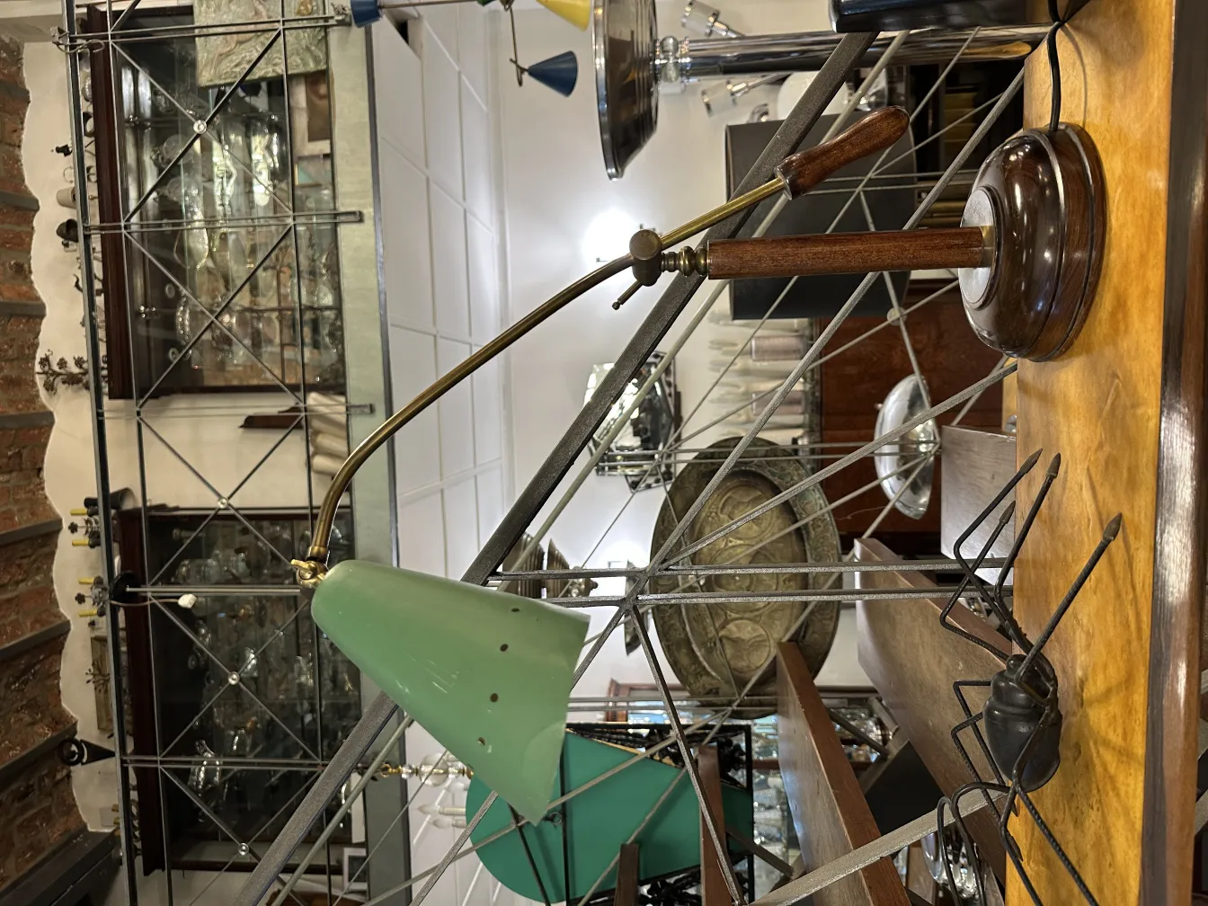 प्राचीन हरे टेबल लैंप, लकड़ी के आधार और समायोज्य हाथ के साथ, एक विंटेज सेटिंग में।